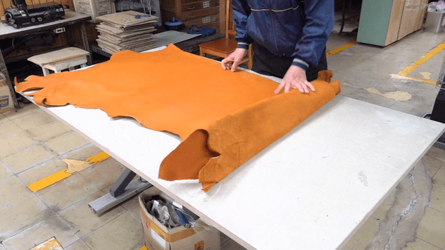 Worker spreading leather on table