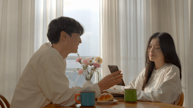 Couple looking at smartphone together by window in morning