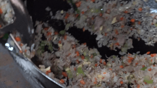 Ladle scooping glossy fried rice from wok