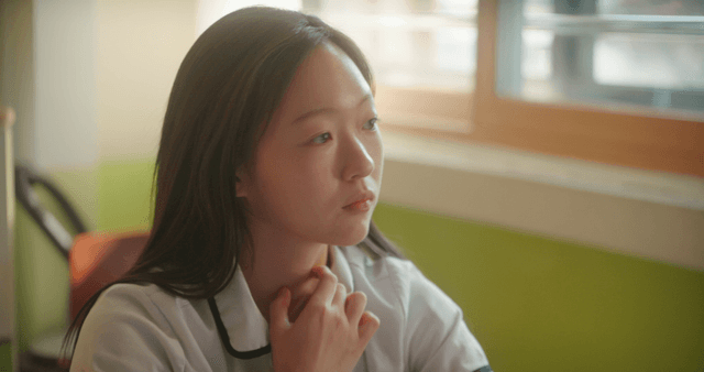 Schoolgirl talking while looking at a desk in a classroom