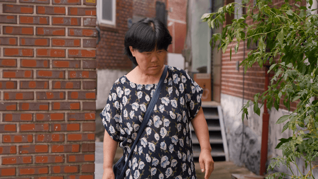 An elderly woman walking down an alley