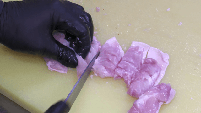 Raw chicken being cut on a cutting board