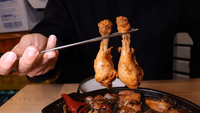 Chopsticks holding braised chicken drumsticks