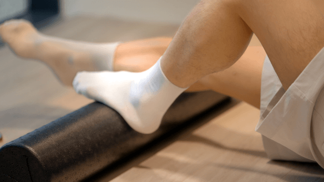 Man using foam roller for leg exercise
