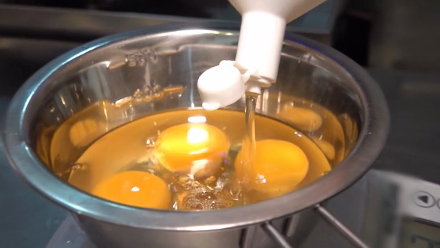 A scene where broth is poured into a bowl containing eggs