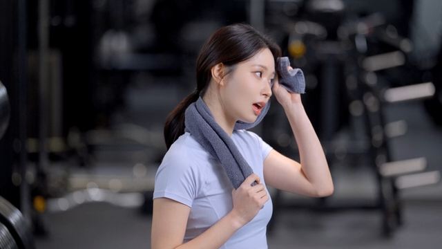 Smiling young woman wiping sweat after workout