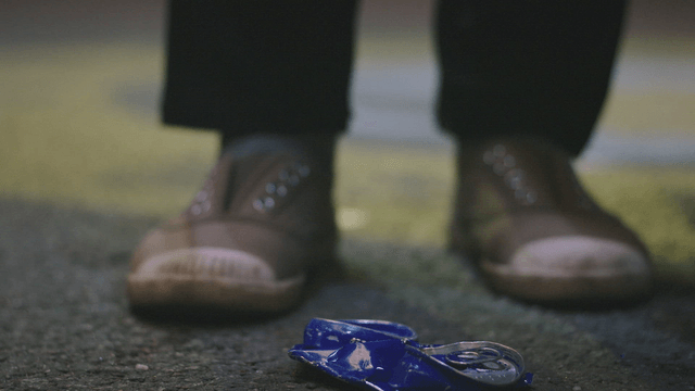 Person picking up a crushed can on the street