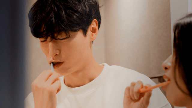 Couple brushing teeth while looking at each other