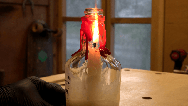 Candle burning in a glass bottle indoors