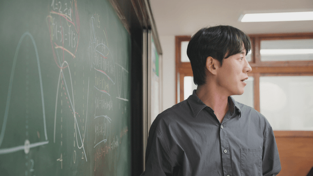 Teacher explaining math on a blackboard