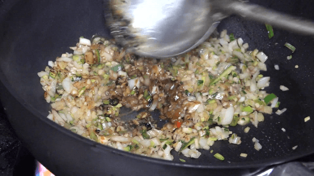 Ladle stir-frying chunjang and vegetables in a hot wok