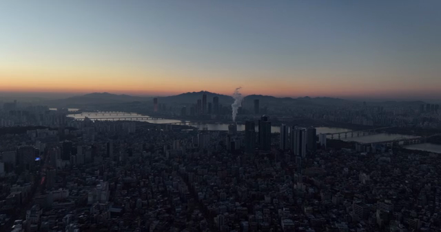A cityscape at dawn with a river and mountains