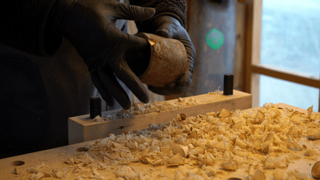 Woodcraft artisan inspecting a large hole in a wooden piece on workbench