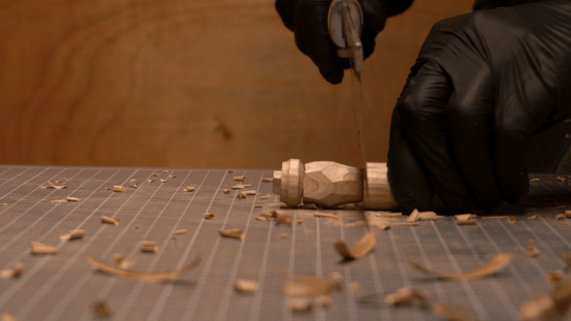 Artisan cutting the top of a wooden piece with a saw
