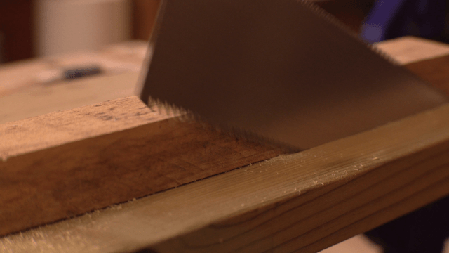 Saw cutting through a wooden plank