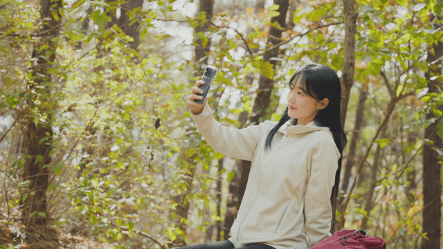 Woman taking selfie on bench in autumn forest
