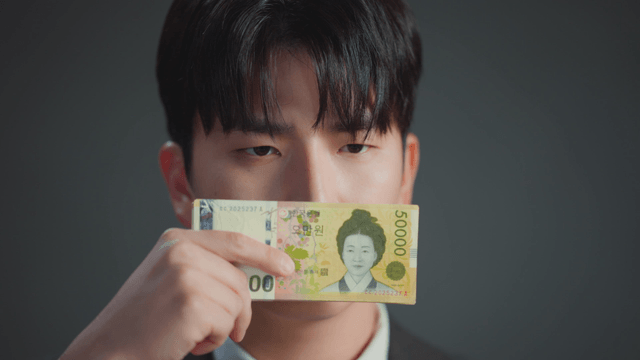 Man covering his mouth with money