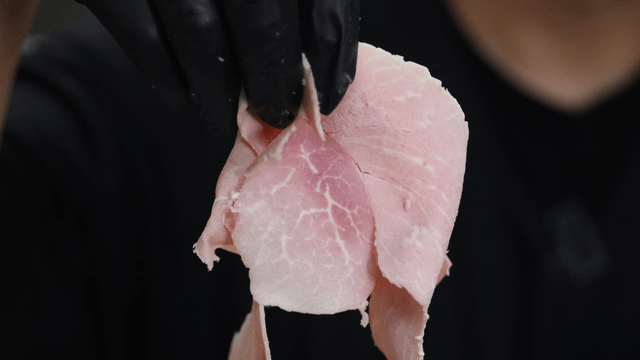Chef holding thinly sliced ham