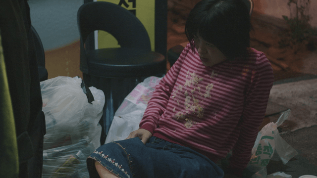 Woman in a vomit-stained t-shirt lying on trash receiving tissue