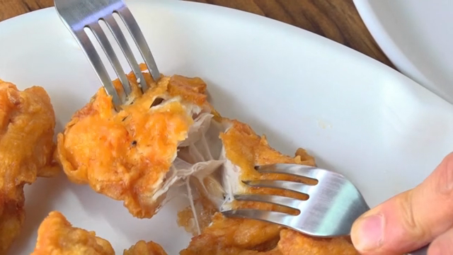 Fried chicken being pulled apart with forks