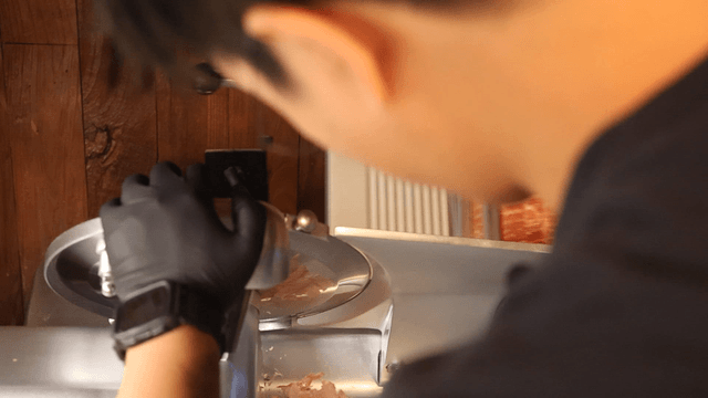Person slicing meat with a machine