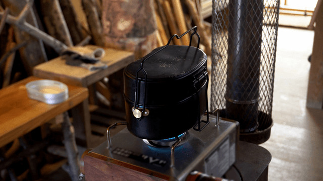 Mess tin boiling on gas burner in workshop