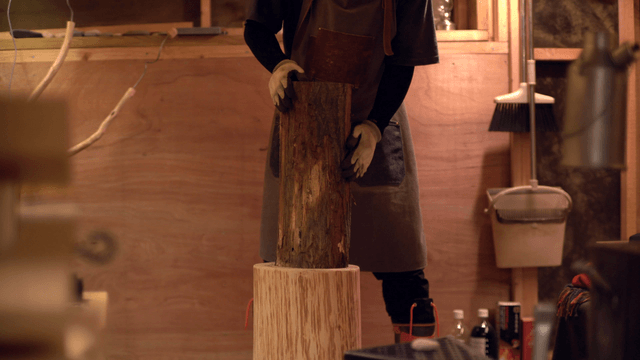 Person preparing to chop wood indoors