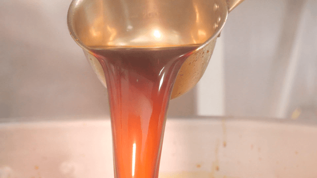 Pouring sauce from a ladle into a pot
