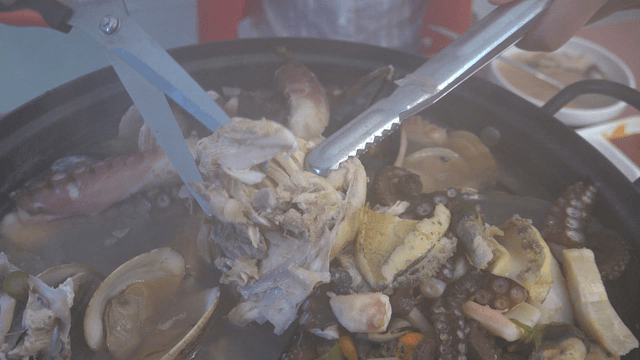 Scissors trimming chicken in chicken and seafood soup