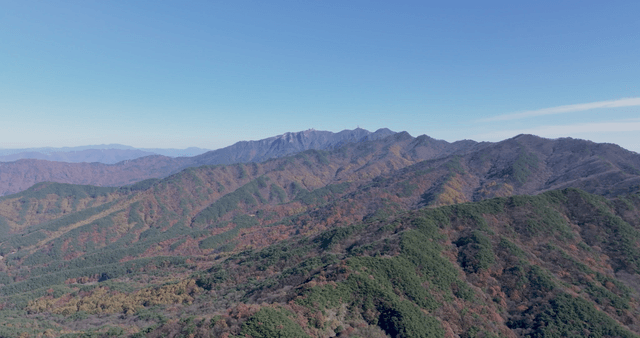 Expansive autumn mountain range under clear sky