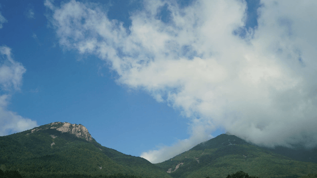 Clouds drifting over green mountains
