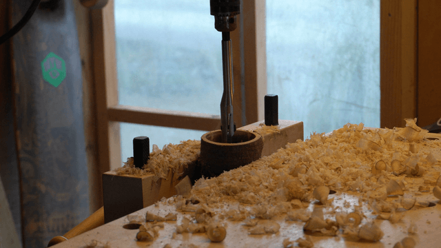 Woodworking with an electric drill widening holes in the workshop