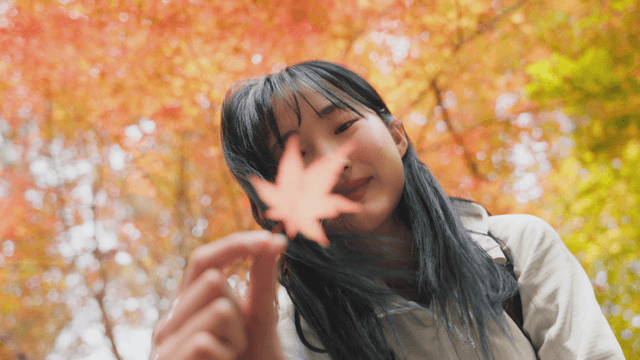 Young woman holding autumn maple leaf