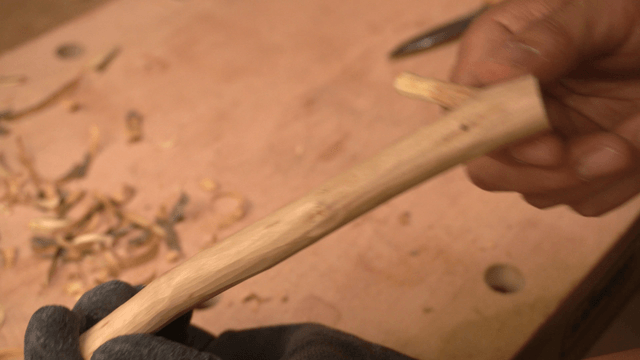 Hand inspecting a carved wooden branch