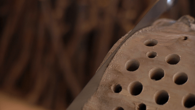 Long saw cutting wood with many holes