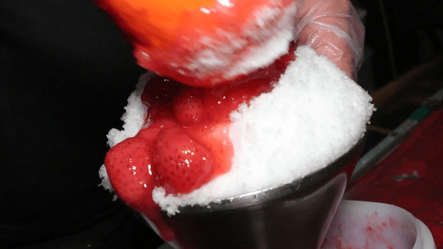 Strawberry syrup poured over shaved ice