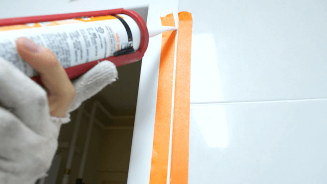 Sealant applied between masking tape on bathroom tiles