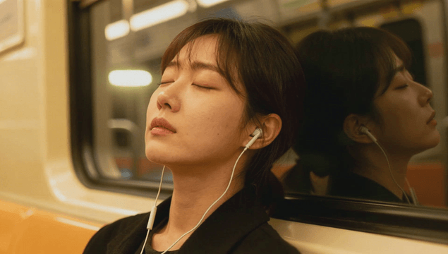 Young woman sleeping with earphones on subway seat