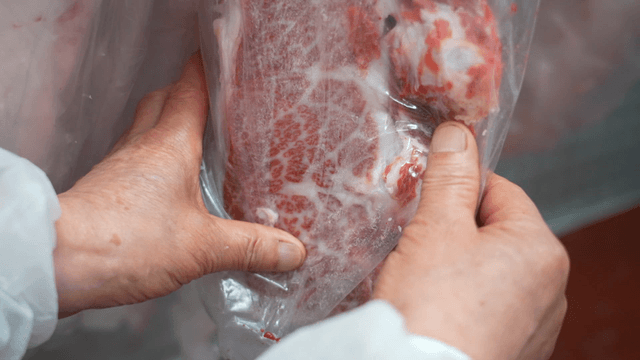 Hand inspecting packaged marbled meat