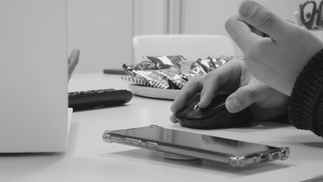 Hands using a mouse on a desk