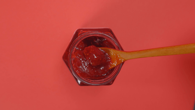 Jar of strawberry jam with a spoon