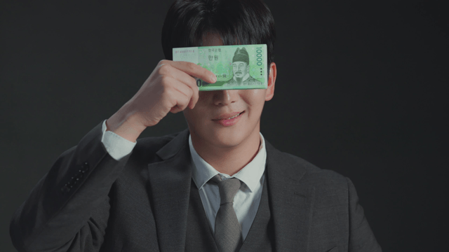 Man showing mixed expressions while covering his face with money