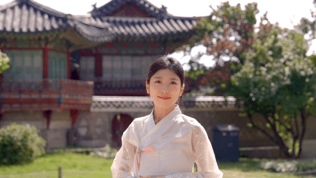 전통 한옥 앞에 선 한복 입은 여성