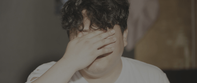 Man in a white shirt squinting in the morning sunlight