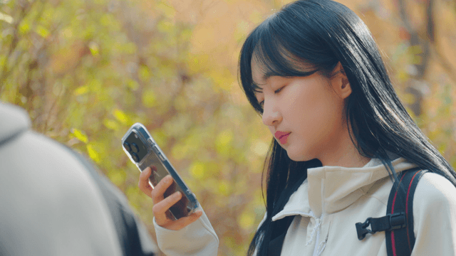 Young woman looking at smartphone in autumn forest