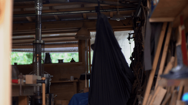 Person resting on a hammock in a woodworking workshop