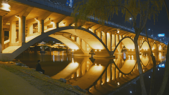 밤에 조용한 강 위의 조명된 다리