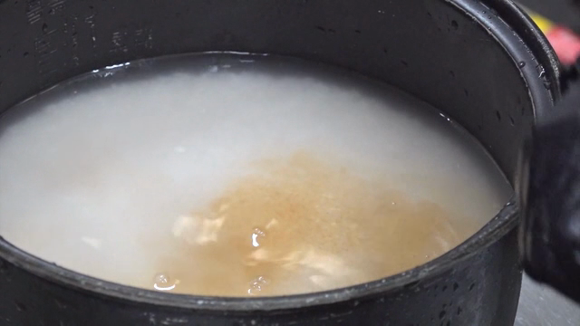 Rice cooking in a pot with a ladle