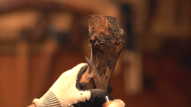 Hands carving wood with a knife indoors