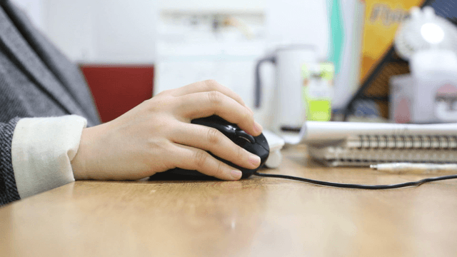 Hand using a computer mouse on a desk
